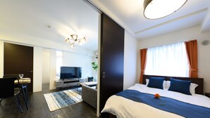 A modern hotel room with a large bed, a desk with a chair, a television, and a dining area. - GLASS YAMAHANA EAST (Sapporo)