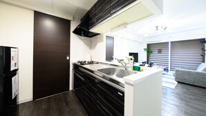 A modern kitchen with dark wood cabinets, a stainless steel sink, and a built-in stove. - GLASS YAMAHANA EAST (Sapporo)