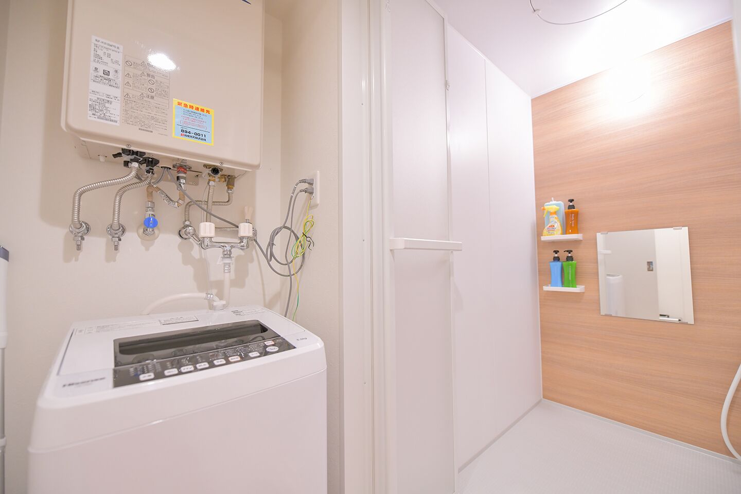 A modern bathroom with a washing machine, a wooden wall, and a shelf with toiletries.