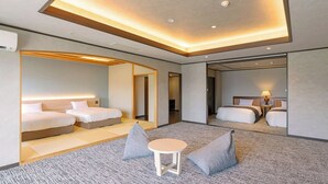 Moderni hotellihuone, jossa on kaksi sänkyä, pieni pyöreä pöytä ja peili.