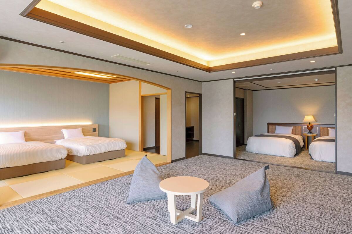 A modern hotel room with two beds, a small round table, and a mirror.