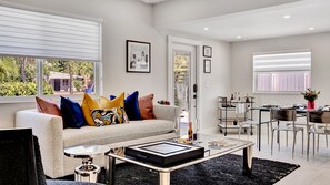 A modern living room with a sofa, coffee table, and dining area.