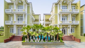 Een symmetrisch hotel met een centrale ingang, meerdere balkons en een bord waarop 
