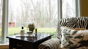 Een kamer met een groot raam, een zwarte tafel met een bloevas en een sofa met een zebraprint.