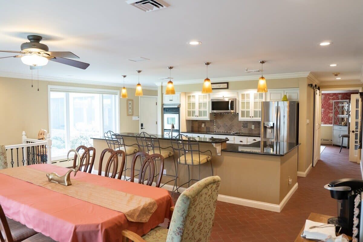 A modern kitchen with a central island, pendant lighting, and a dining area with a table and chairs.