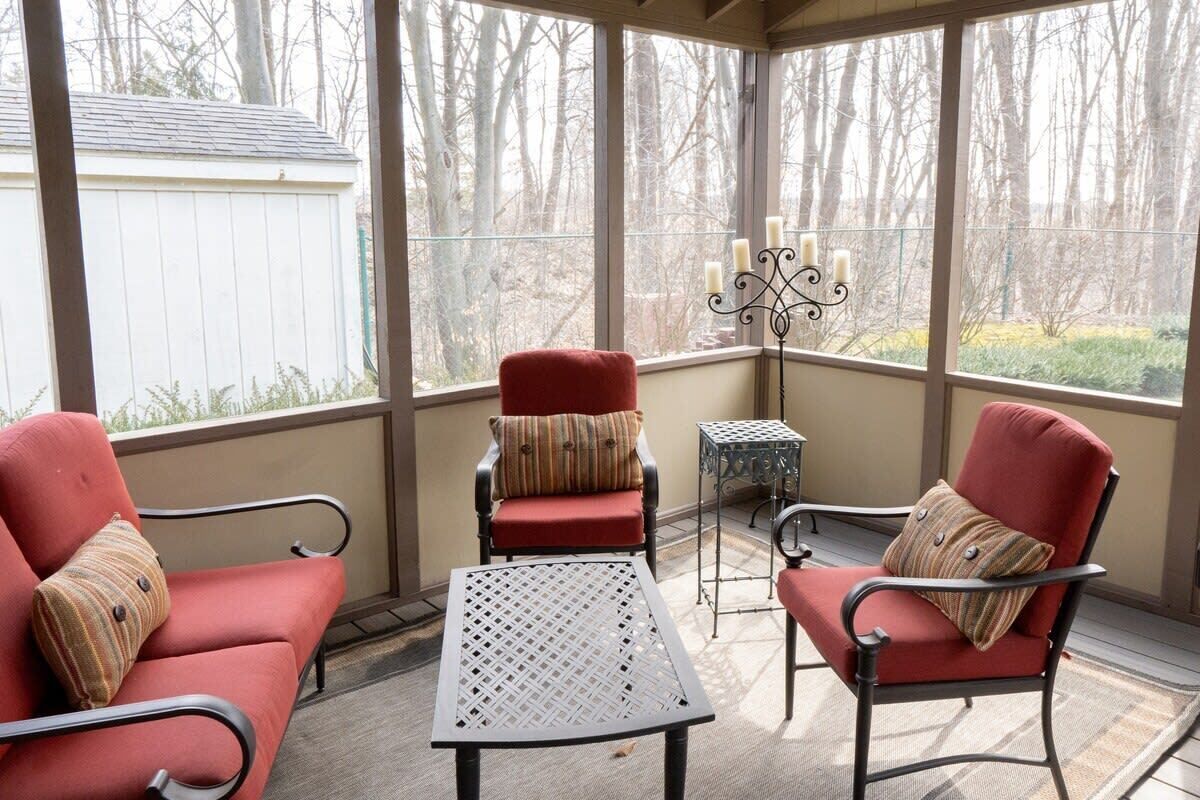 A covered patio with two red chairs, a small table, and a decorative candelabra.