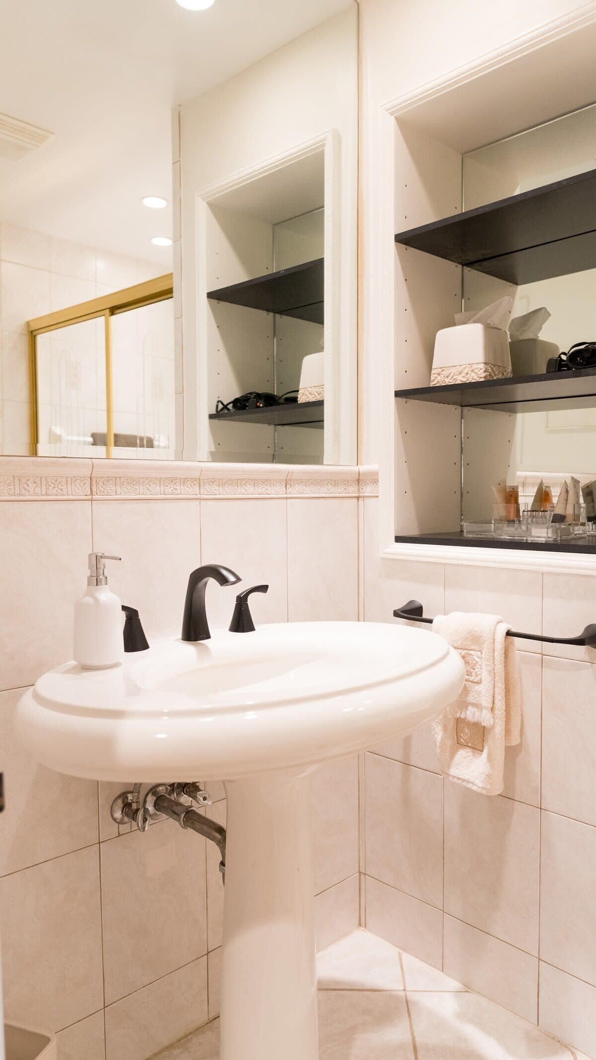 Une salle de bain avec un lavabo blanc, un miroir et un porte-serviettes.