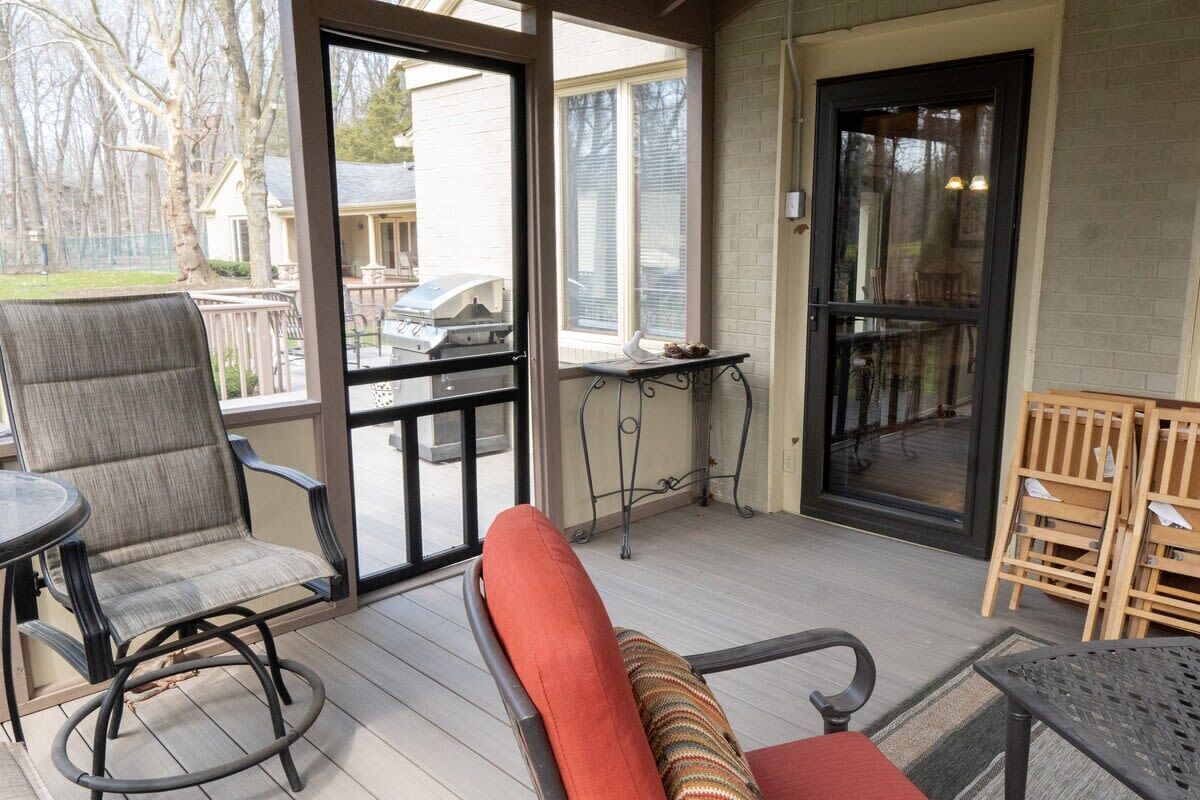 An outdoor patio with a chair, a table, and a grill.