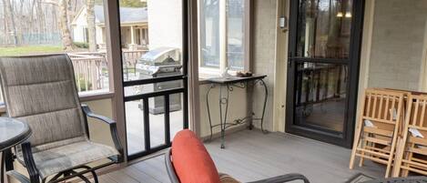 An outdoor patio with a chair, a table, and a grill.