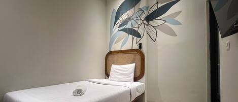 A single bed with a wooden headboard, a white pillow, and a wall-mounted air conditioner.