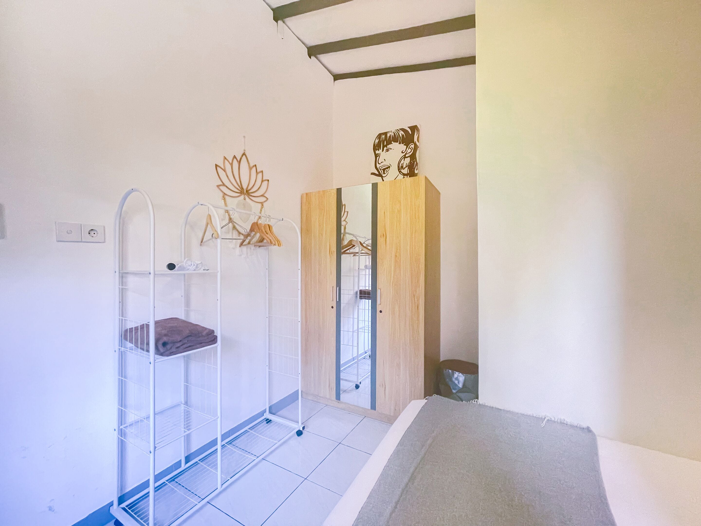 Une chambre avec un lit superposé, une armoire en bois, un miroir et un porte-manteau fixé au mur.