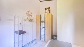 Une chambre avec un lit superposé, une armoire en bois, un miroir et un porte-manteau fixé au mur.