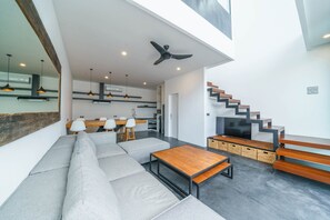 A modern living area with a sofa, a wooden coffee table, and a staircase leading to an upper level. - Loft Carolyn (Canggu)