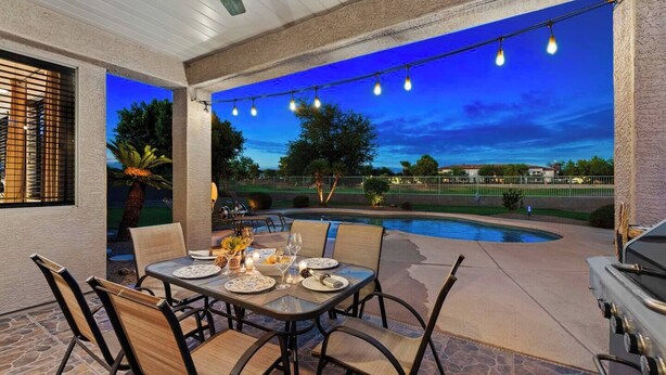 Un patio exterior con una mesa de comedor dispuesta para cuatro personas, rodeada de sillas.