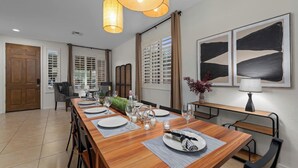 Un comedor con una larga mesa de madera dispuesta para seis comensales, con sillas a ambos lados y un banco a lo largo de la pared.