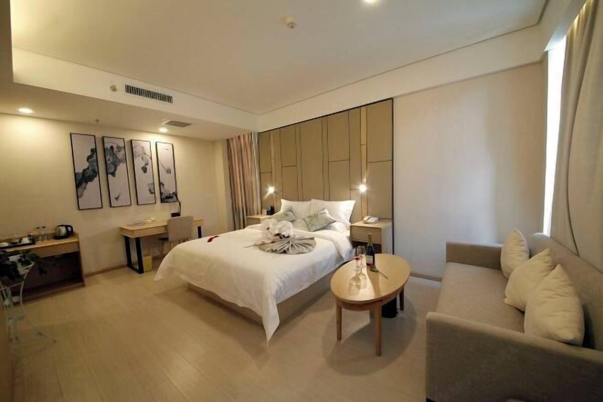 Une chambre d’hôtel moderne, équipée d’un lit, d’un bureau, d’une chaise, d’un canapé et ornée d’œuvres d’art sur les murs.