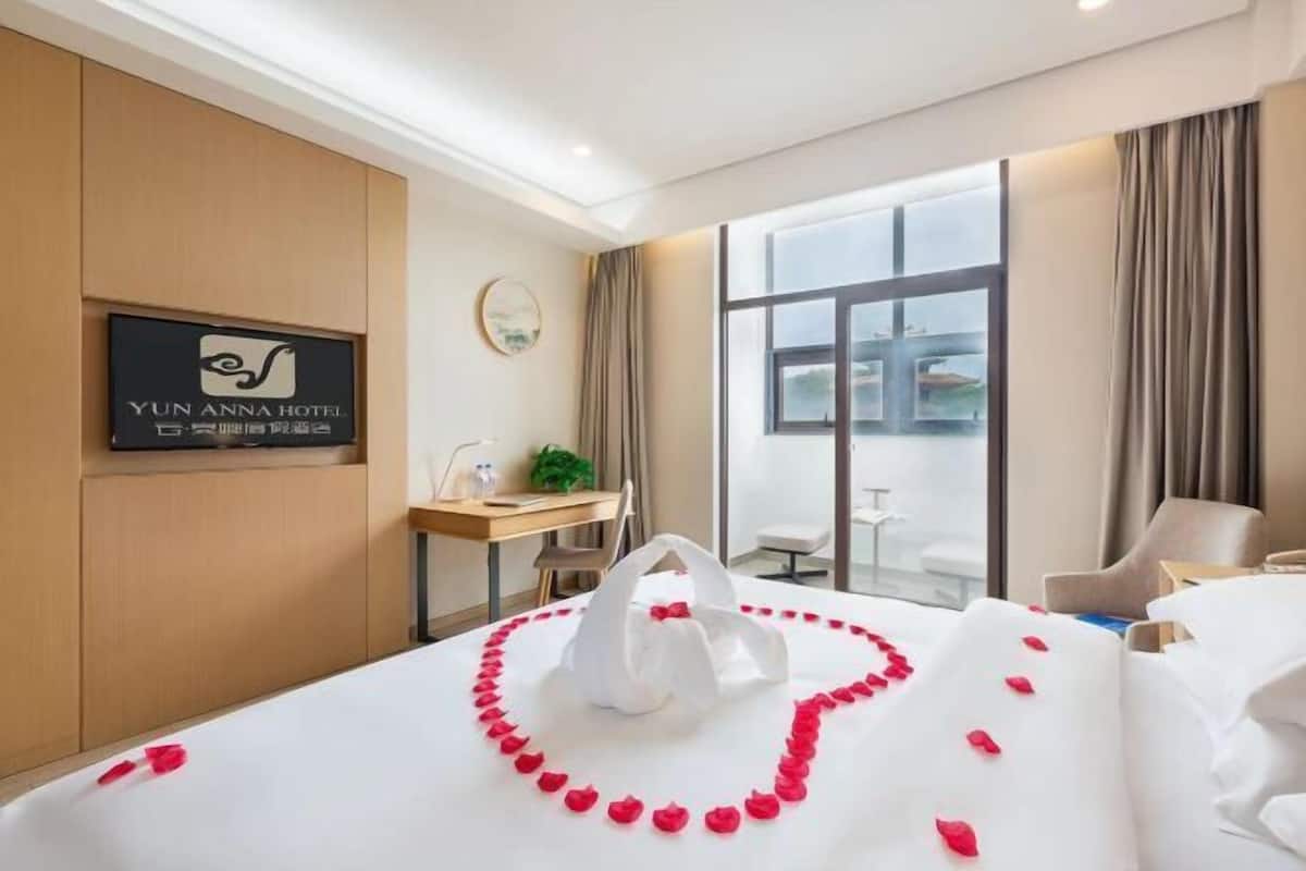 Une chambre d’hôtel avec un lit, un bureau, une chaise et une fenêtre donnant sur un paysage agréable.