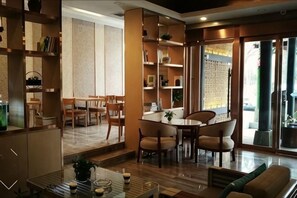 A spacious living area with a dining table, chairs, and a sofa. There are bookshelves and a coffee table. - Cloud Anna Hotel (Longli)
