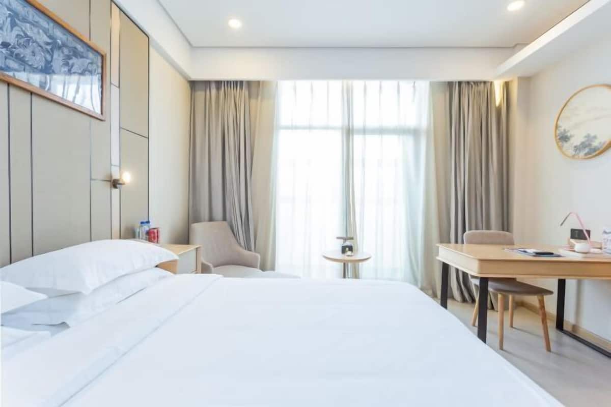 Habitación de hotel con una cama grande, un escritorio, una silla y una mesita.