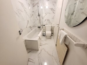 Bathroom features a bathtub, toilet, and large mirror above the sink.