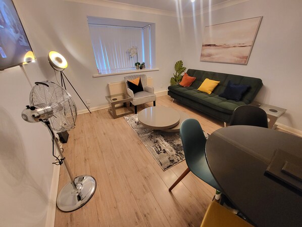 Relax in this stylish living room with a green sofa, round coffee table, and large window.