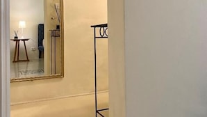 A hallway with a large mirror, a small table with a lamp, and a tall black stand.