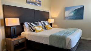 A neatly arranged hotel room with a large bed, two bedside tables with lamps, and two wall-mounted paintings. - The Pool Resort Kingscliff - One Bedroom Ocean and Pool View (4314) - Holiday Management Co. (Tweed)