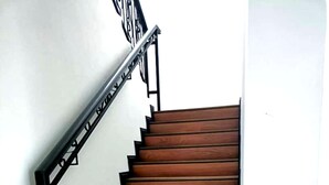 A wooden staircase with black handrails and a white wall. - OYO HOME 90769 Flo Inn Homestay Bsi (Tawau)