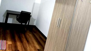A room with a wooden floor, a black chair, and a wardrobe with two doors. - OYO HOME 90769 Flo Inn Homestay Bsi (Tawau)