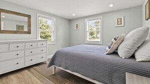 A bedroom with a bed, dresser, and windows.
