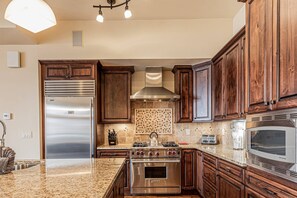 Una cocina moderna con electrodomésticos de acero inoxidable, armarios de madera y salpicadero de azulejos.