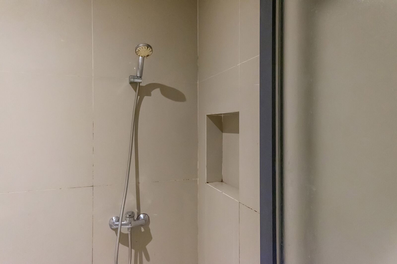 A shower with a handheld showerhead and a wall-mounted control.