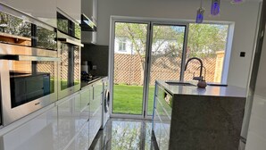Eine moderne Küche mit einer Schiebetür aus Glas, die in einen Garten führt.