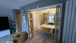 Ein modernes Wohnzimmer mit Fernseher, einem grünen Sitzsack und einem Essbereich mit Tisch und Stühlen.