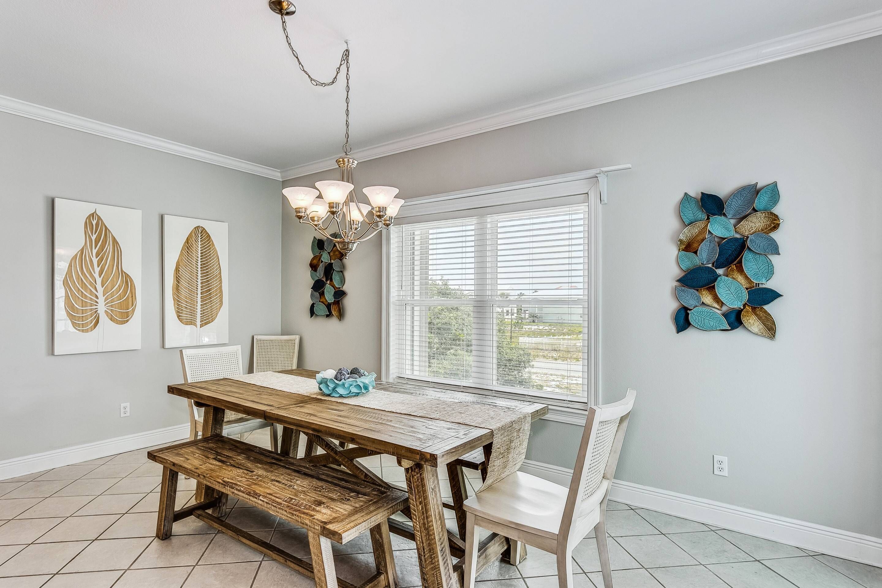 A dining room with a wooden table and benches, a chandelier, and wall art.