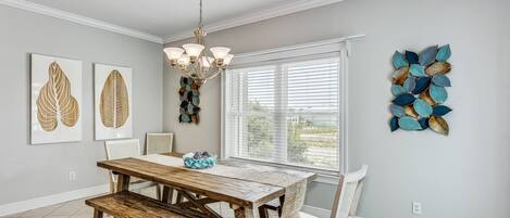 A dining room with a wooden table and benches, a chandelier, and wall art.