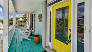 A porch with a teal floor, white railings, and a yellow door with a glass panel. - Private Saltwater Heated Pool |8 Bikes |Walk to Johnson Beach |Single Level |Screened Lanai (Pensacola)