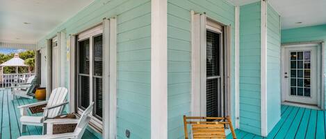 A turquoise wooden porch with white-framed windows and white railings.