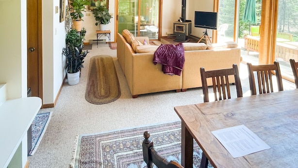 A spacious living room with a high wooden ceiling, a fireplace, a large window, and a dining area.