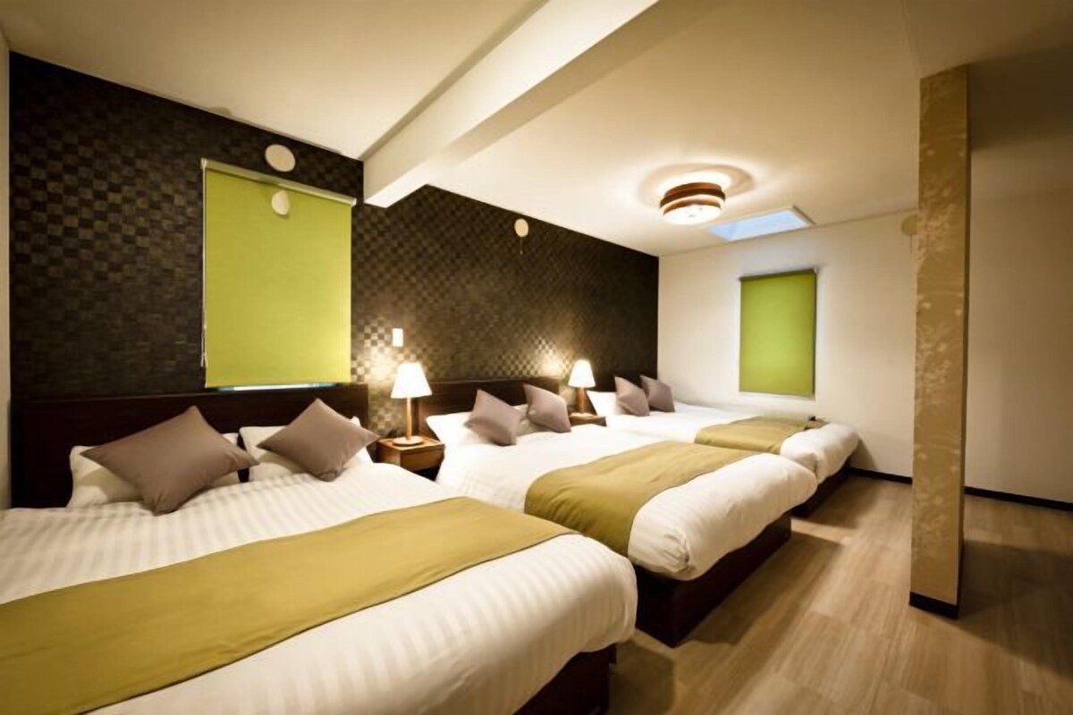 Habitación de hotel con tres camas, un ventanal grande y un diseño moderno.