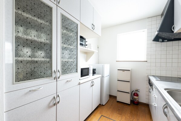Una cocina con armarios blancos, microondas, refrigerador y lavaplatos.