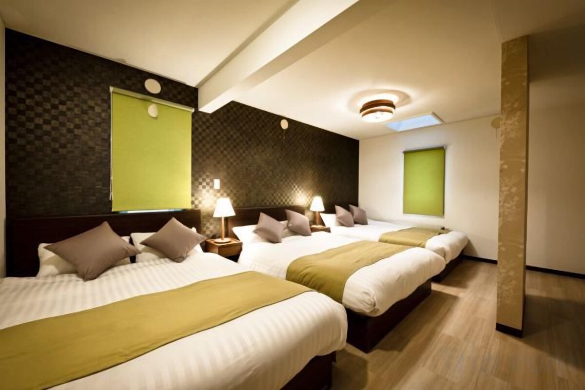 A hotel room with three beds, a large window, and a modern design.