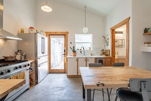 Enjoy meal preparation and dining in this kitchen with a central island, stove, and refrigerator, opening to a dining area with a wooden table and chairs.