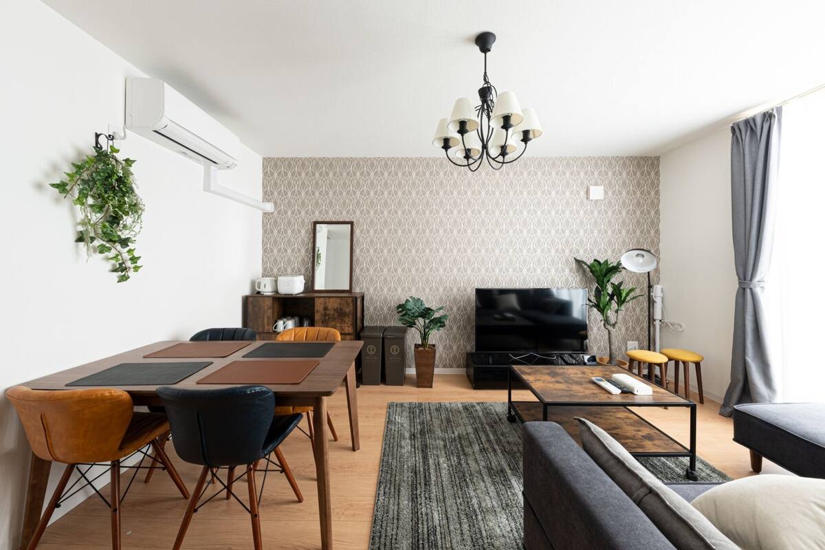 A modern living room with a dining area, a sofa, a TV, and a chandelier.