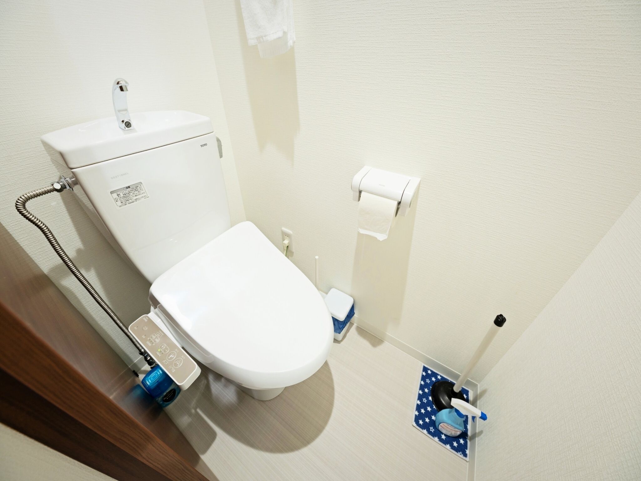 A modern bathroom with a white toilet, a toilet paper holder, and a bidet.