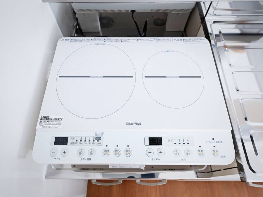 A white induction cooktop with a digital display and control buttons.