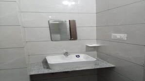 A bathroom with a white sink, a mirror, and a towel dispenser.