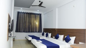 A hotel room with two beds, a wooden headboard, a ceiling fan, a TV, and a window with curtains.