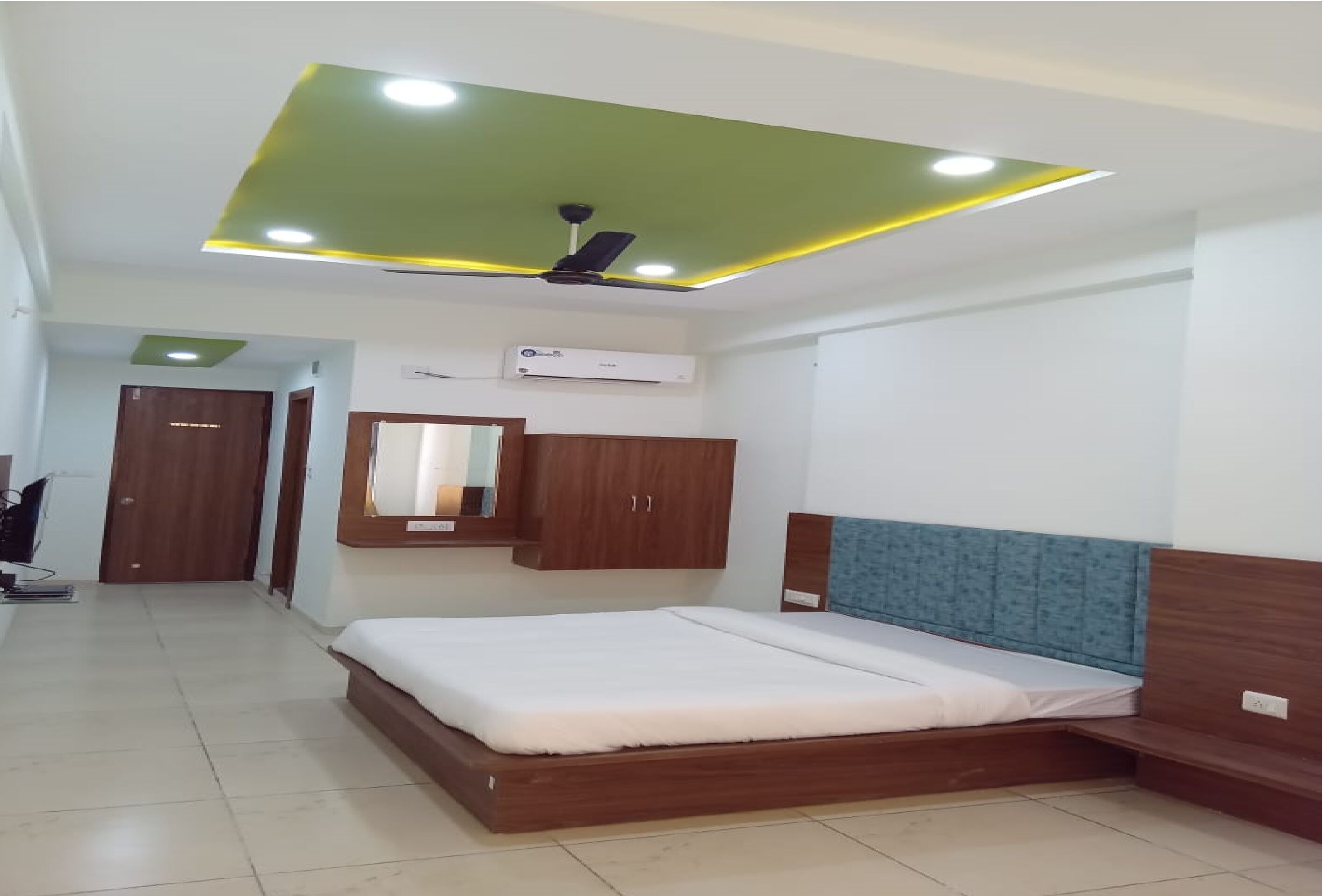 A bedroom with a bed, wooden headboard, a ceiling fan, recessed lighting, and an air conditioning unit.
