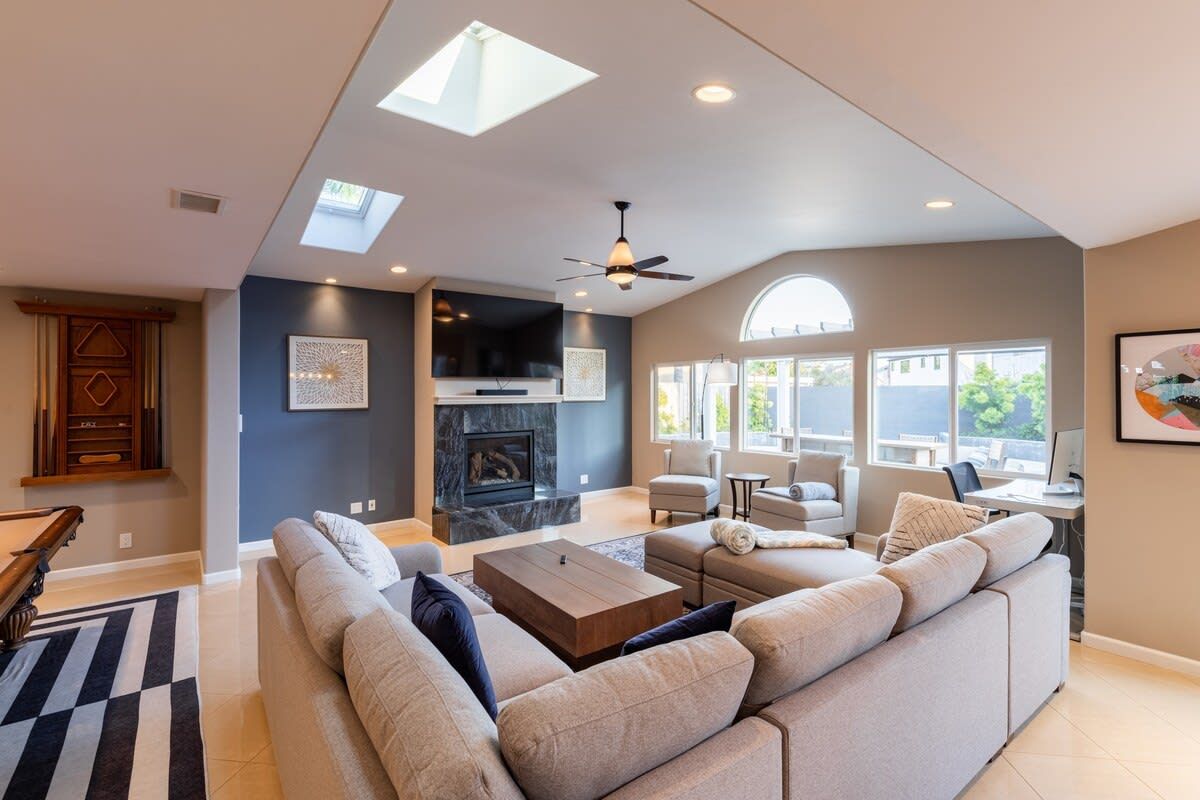 A modern living room with a fireplace, sofa, and a ceiling fan.